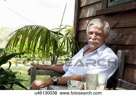 Senior man relaxing by wooden cabin, Raglan, New Zealand View Large Photo Image Stock Photo - Senior man relaxing by wooden cabin, Raglan, New Zealand. Fotosearch