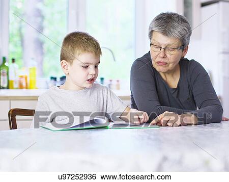Senior woman reading storybook with grandson at kitchen table View Large Photo Image Stock Photograph - Senior woman reading storybook with grandson at kitchen table. Fotosearch