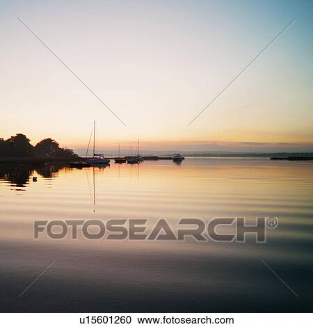 Stock Image - Silhouetted sunset view of harbor on Lough Derg, Ireland. Fotosearch