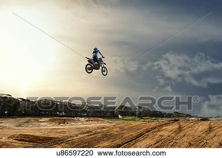Silhouetted young male motocross racer jumping mid air over mud track View Large Photo Image Stock Image - Silhouetted young male motocross racer jumping mid air over mud track. Fotosearch