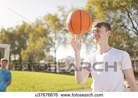 Smiling young male basketball player balancing basketball on finger View Large Photo Image Stock Photograph - Smiling young male basketball player balancing basketball on finger. Fotosearch