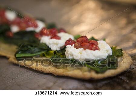 Picture - Spanish tapas with spinach, soft cheese and pomegranate seeds on flatbread. Fotosearch