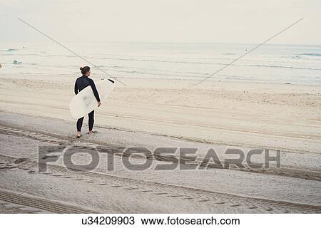 Stock Image - Surfer with surfboard on beach, Lacanau, France. Fotosearch