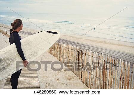 Stock Image - Surfer with surfboard on beach, Lacanau, France. Fotosearch