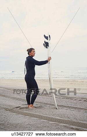Stock Photo - Surfer with surfboard on beach, Lacanau, France. Fotosearch