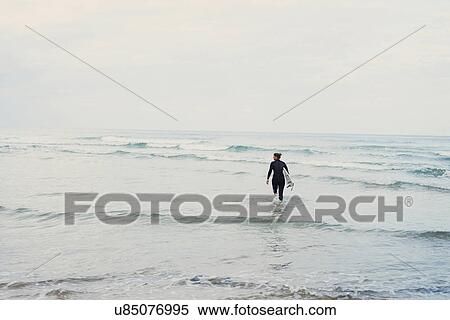 Surfer with surfboard walking into ocean, Lacanau, France View Large Photo Image Stock Photography - Surfer with surfboard walking into ocean, Lacanau, France. Fotosearch