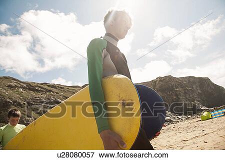 Stock Photo - Teenage boy carrying surfboard. Fotosearch