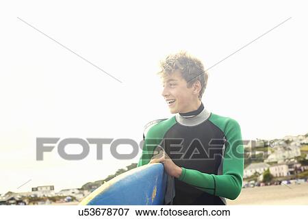 Teenage boy carrying surfboard View Large Photo Image Stock Photo - Teenage boy carrying surfboard. Fotosearch
