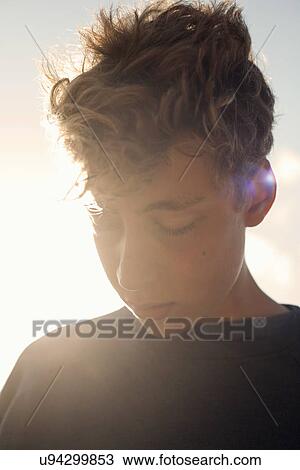 Stock Image - Teenage boy looking down, close up. Fotosearch