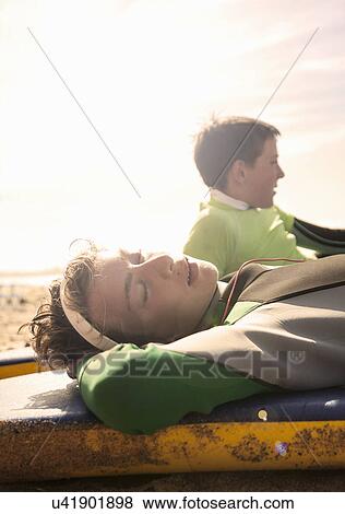 Teenage boy lying asleep on surfboard View Large Photo Image Stock Photo - Teenage boy lying asleep on surfboard. Fotosearch