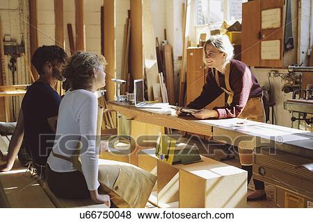 Stock Photo - Three craft workers having an informal meeting in pipe organ workshop. Fotosearch
