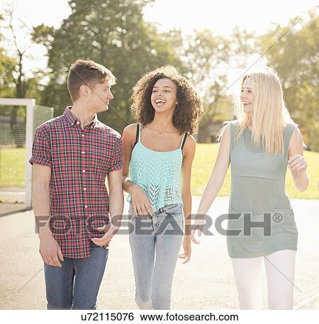 Three young adult friends strolling in park View Large Photo Image Stock Photograph - Three young adult friends strolling in park. Fotosearch