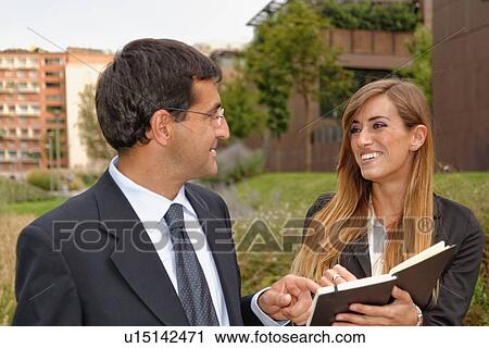 Two adults having discussion, looking at notebook View Large Photo Image Stock Image - Two adults having discussion, looking at notebook. Fotosearch