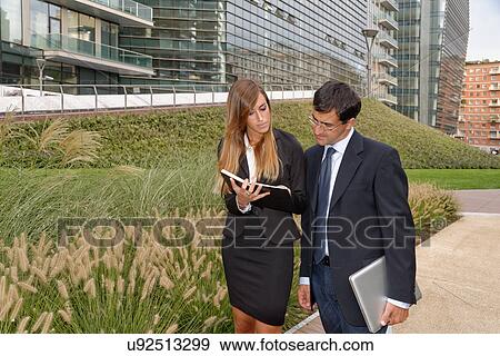 Two adults having discussion, looking at notebook View Large Photo Image Stock Photo - Two adults having discussion, looking at notebook. Fotosearch