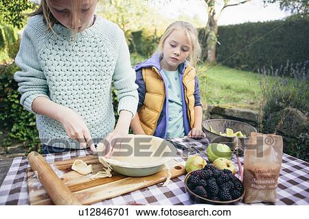 Stock Image - Two girls making a pie. Fotosearch