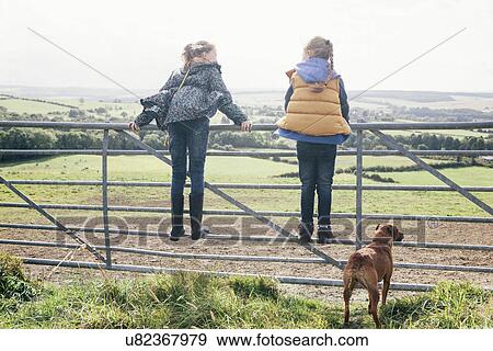 Two girls standing on metal gate View Large Photo Image Stock Photo - Two girls standing on metal gate. Fotosearch