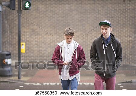 Stock Image - Two male friends crossing road. Fotosearch