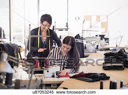 Stock Photography - Two seamstresses at sewing machine in workshop. Fotosearch