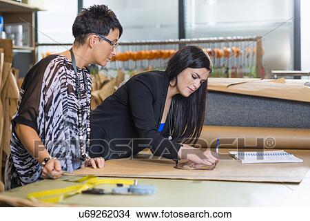Picture - Two seamstresses drawing dressmakers pattern in workshop. Fotosearch