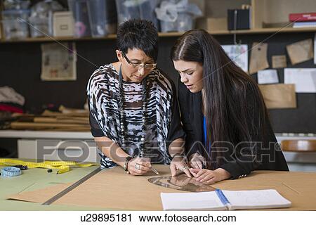 Two seamstresses using curved ruler on dressmakers pattern in workshop View Large Photo Image Stock Image - Two seamstresses using curved ruler on dressmakers pattern in workshop. Fotosearch
