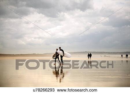 Two surfers carrying surfboards on Saunton Beach, Devon, England, UK View Large Photo Image Stock Image - Two surfers carrying surfboards on Saunton Beach, Devon, England, UK. Fotosearch