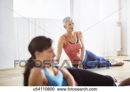 Stock Image - Two women lying on side in pilates class. Fotosearch