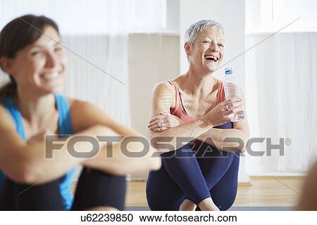 Stock Image - Two women taking a break in pilates class. Fotosearch