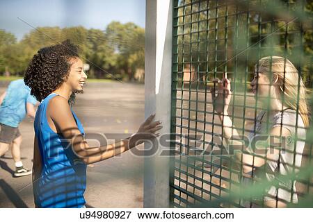 Two young female basketball players chatting on opposite wire fence View Large Photo Image Stock Photo - Two young female basketball players chatting on opposite wire fence. Fotosearch