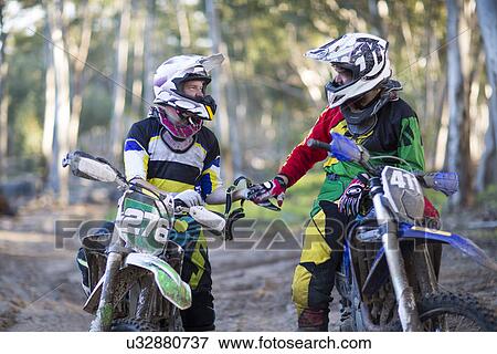 Two young male motocross riders chatting on forest track View Large Photo Image Stock Photo - Two young male motocross riders chatting on forest track. Fotosearch