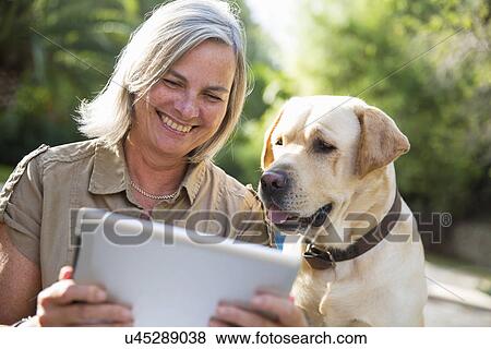 Woman and dog looking at digital tablet View Large Photo Image Stock Photo - Woman and dog looking at digital tablet. Fotosearch