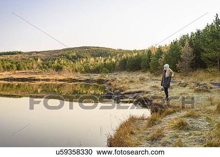 Stock Image - Woman by lake, Reykjavik, Iceland. Fotosearch