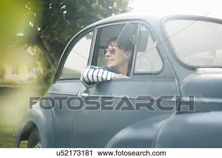 Stock Image - Woman in a vintage car. Fotosearch