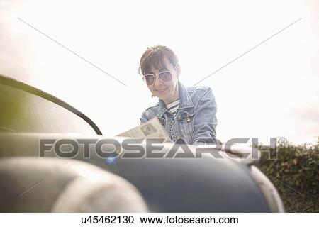 Stock Image - Woman leaning on vintage car. Fotosearch