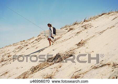 Stock Image - Woman with surfboard on beach, Lacanau, France. Fotosearch