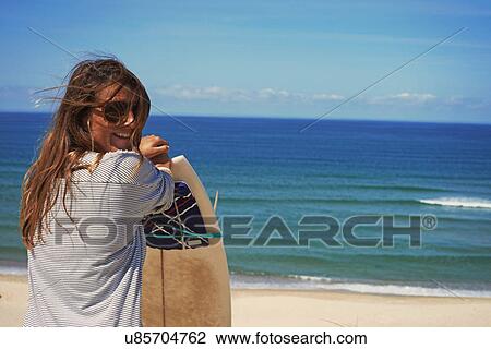 Stock Image - Woman with surfboard on beach, Lacanau, France. Fotosearch