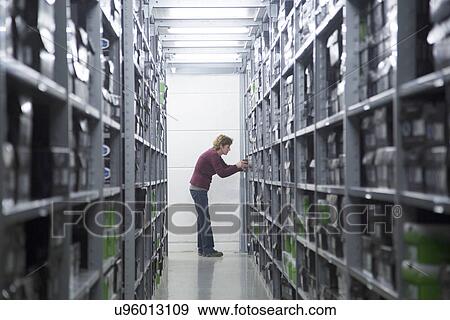Stock Photo - Worker searching for stock at healthcare warehouse. Fotosearch