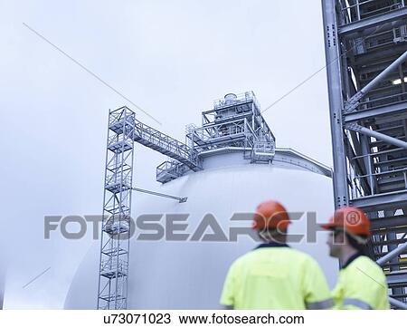 Stock Image - Workers at biomass facility, low angle view. Fotosearch