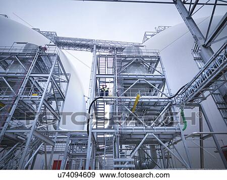 Workers at biomass facility, low angle view View Large Photo Image Stock Photo - Workers at biomass facility, low angle view. Fotosearch
