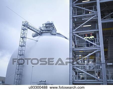 Workers at biomass facility, low angle view View Large Photo Image Stock Photo - Workers at biomass facility, low angle view. Fotosearch