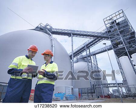 Stock Image - Workers using digital tablet at biomass facility. Fotosearch