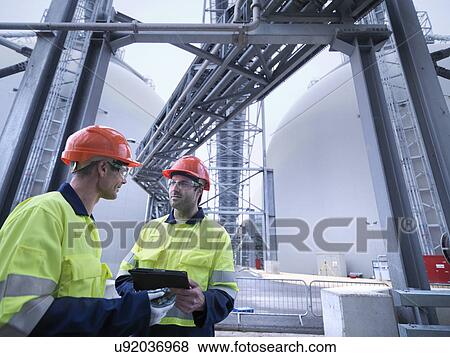 Workers using digital tablet at biomass facility View Large Photo Image Stock Photo - Workers using digital tablet at biomass facility. Fotosearch