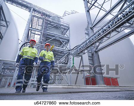 Workers walking through biomass facility, low angle view View Large Photo Image Stock Image - Workers walking through biomass facility, low angle view. Fotosearch