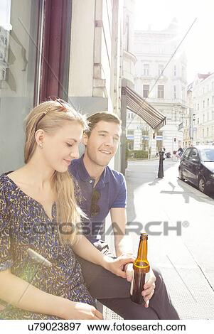 Stock Photo - Young couple at sidewalk cafe drinking beer. Fotosearch
