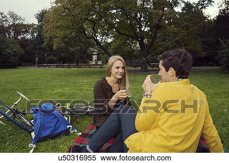 Young couple drinking wine on picnic blanket in park View Large Photo Image Stock Photography - Young couple drinking wine on picnic blanket in park. Fotosearch