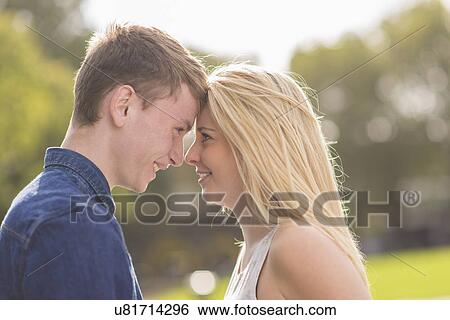 Young couple facing each other in park View Large Photo Image Stock Photograph - Young couple facing each other in park. Fotosearch