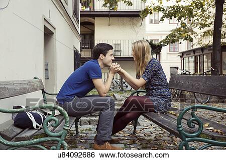 Young couple holding hands from opposite park benches View Large Photo Image Stock Photograph - Young couple holding hands from opposite park benches. Fotosearch
