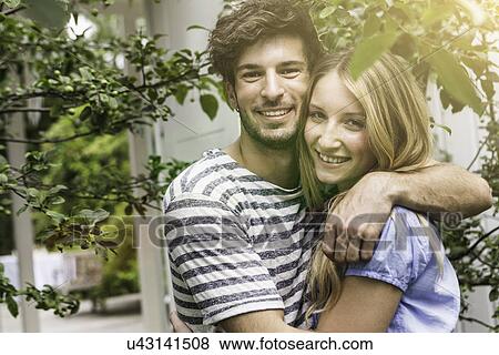 Stock Photo - Young couple hugging in garden. Fotosearch
