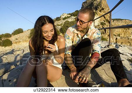 Picture - Young couple sitting chatting at coast, Marseille, France. Fotosearch