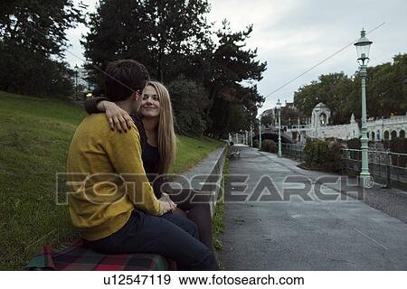 Young couple sitting face to face on park wall View Large Photo Image Stock Photo - Young couple sitting face to face on park wall. Fotosearch