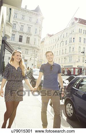 Young couple strolling along city street View Large Photo Image Stock Image - Young couple strolling along city street. Fotosearch